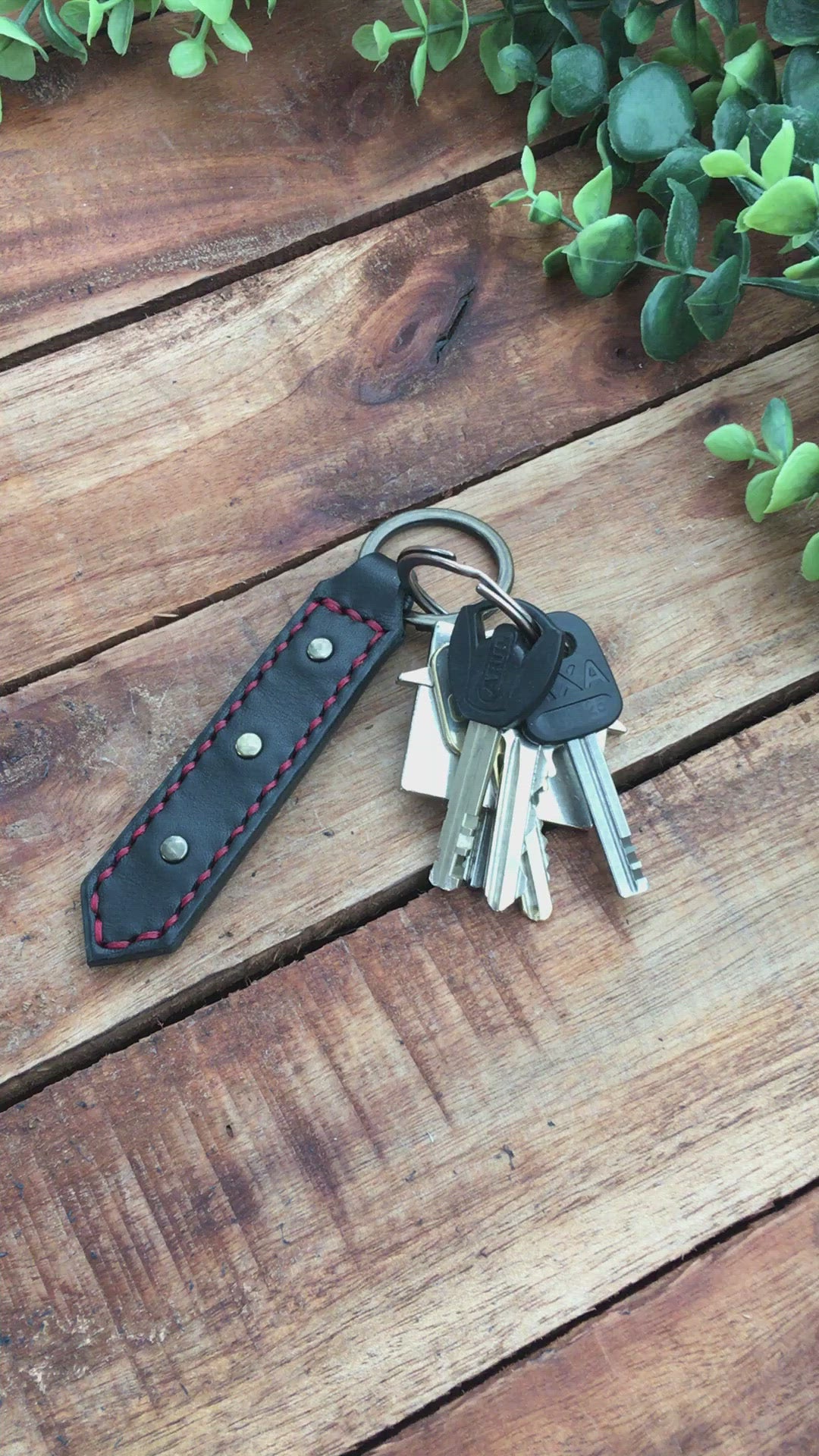 Video showing a Handmade Black Leather Studded Keychain with Red Stitching