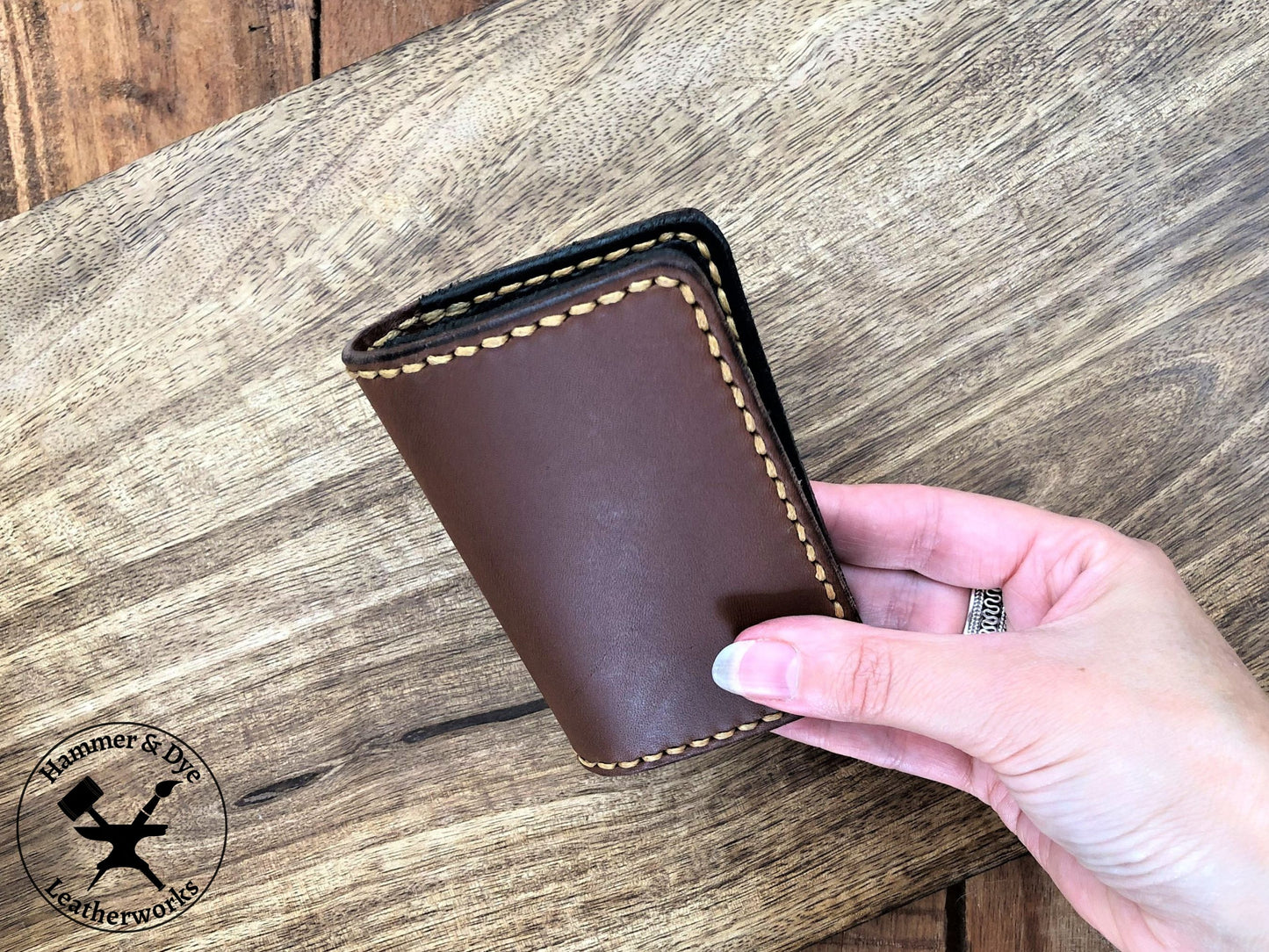Handmade Two-tone Bifold Leather Card Wallet in Brown and Black with Hazel Stitching held in a hand