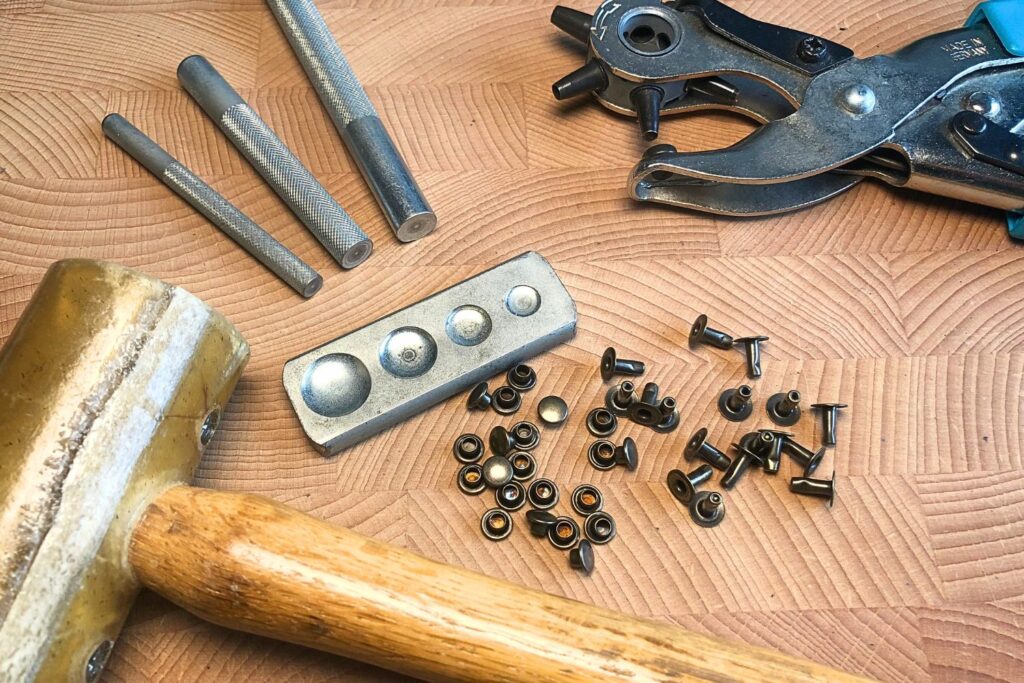 The Beginner's Leathercraft Tool Guide 6 Rivet setter, rivets, hole punch and mallet on a wooden background