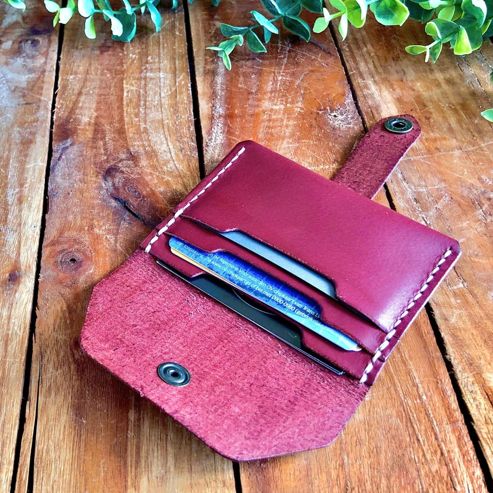 magenta leather card wallet filled with cards on a rustic wooden background
