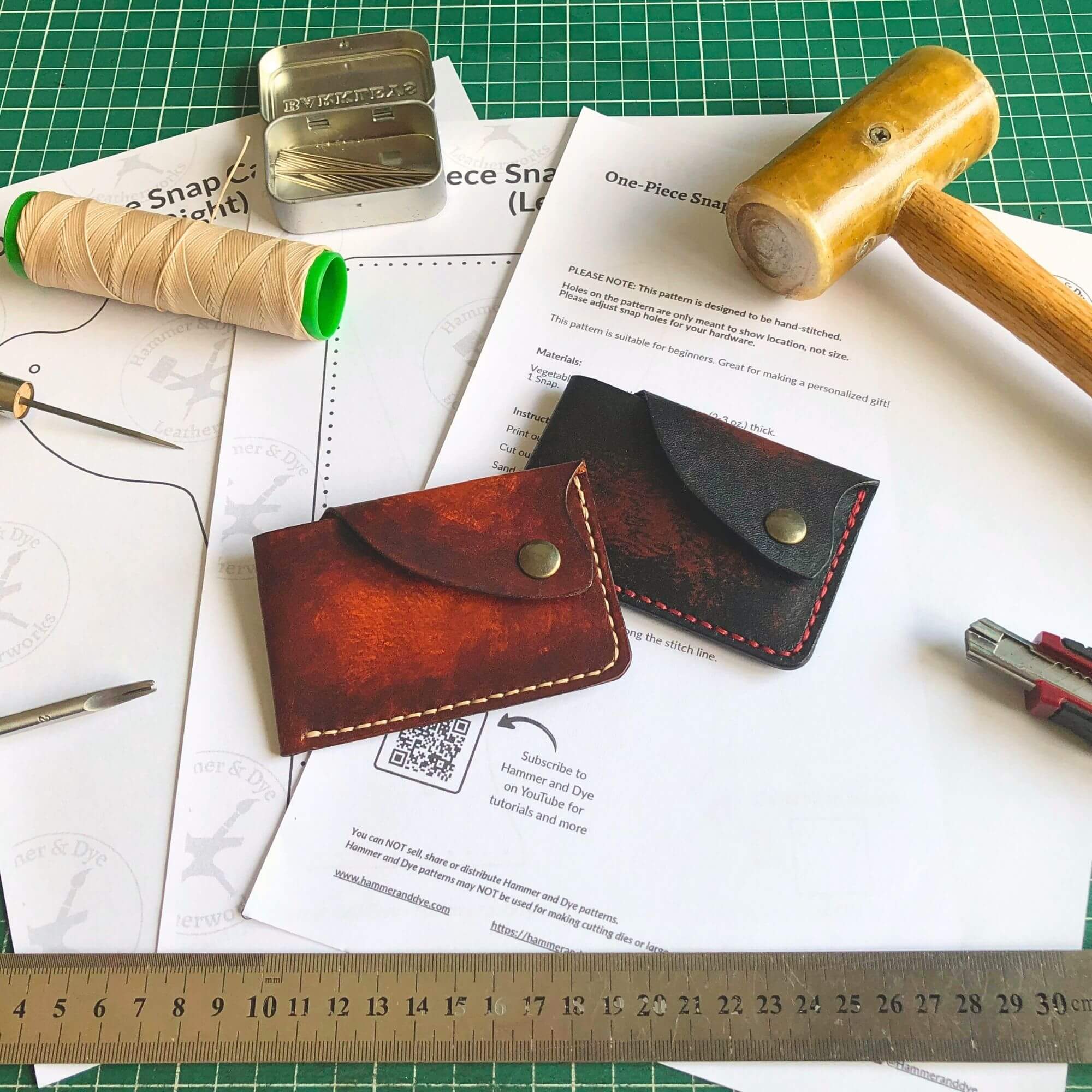 one-piece snap card wallet pattern surrounded by leathercraft tools and the finished wallet