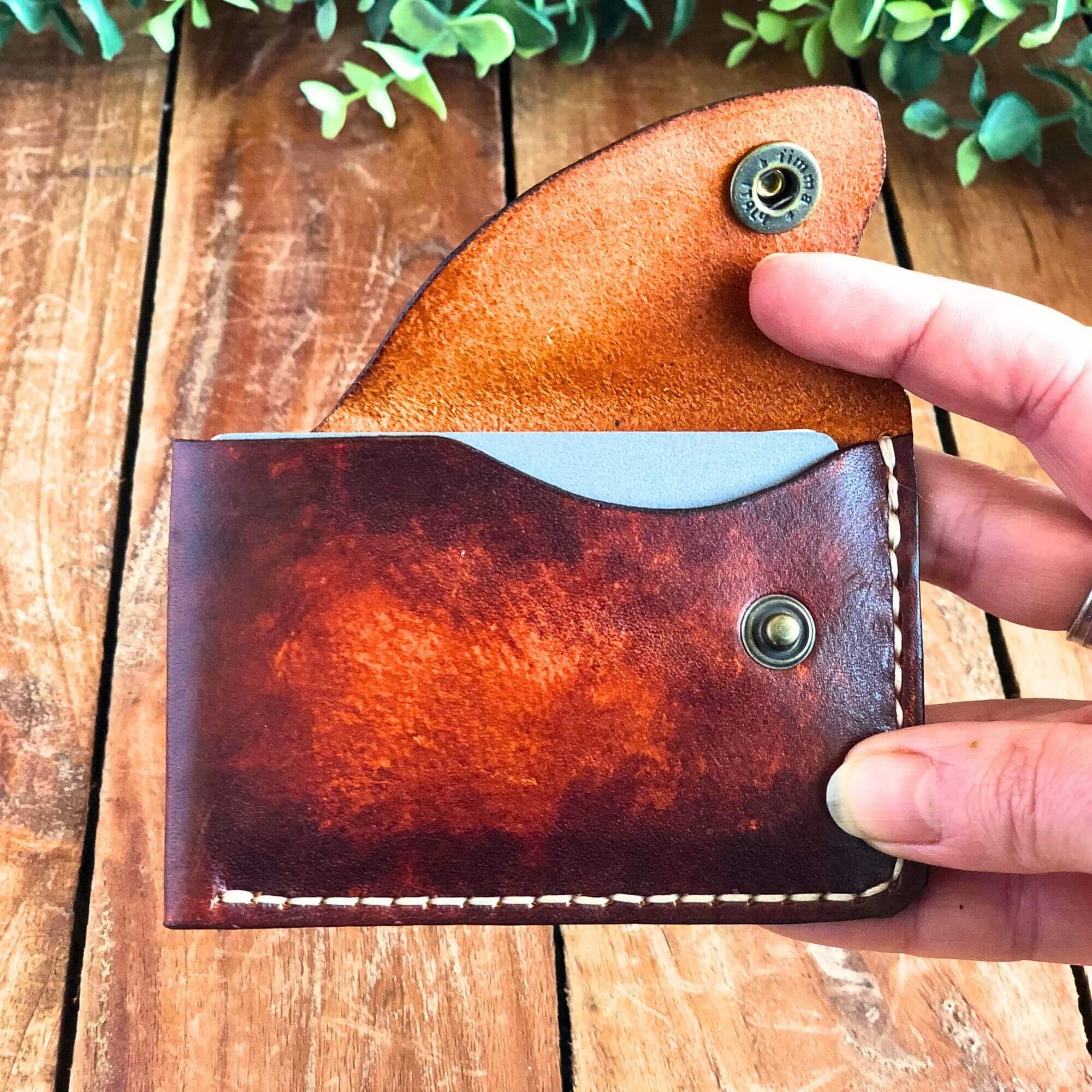 compact leather card wallet filled with cards held in a hand