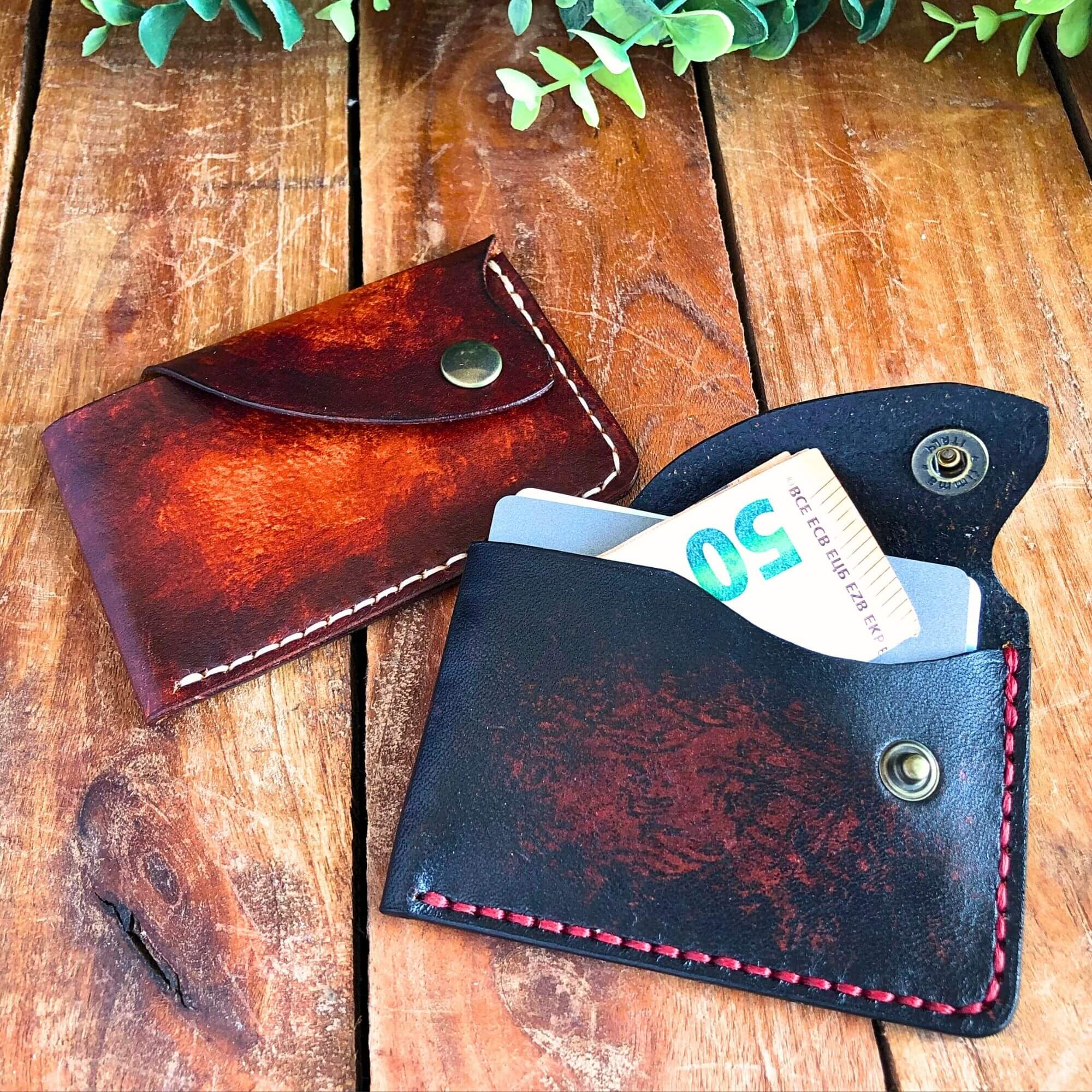 2 leather card wallets with snap closure on a rustic wooden background