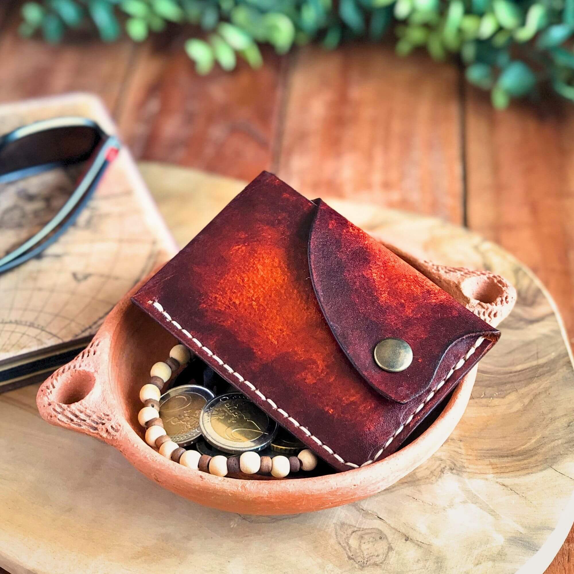 brown snap card wallet with strong patina in a tray with personal belongings