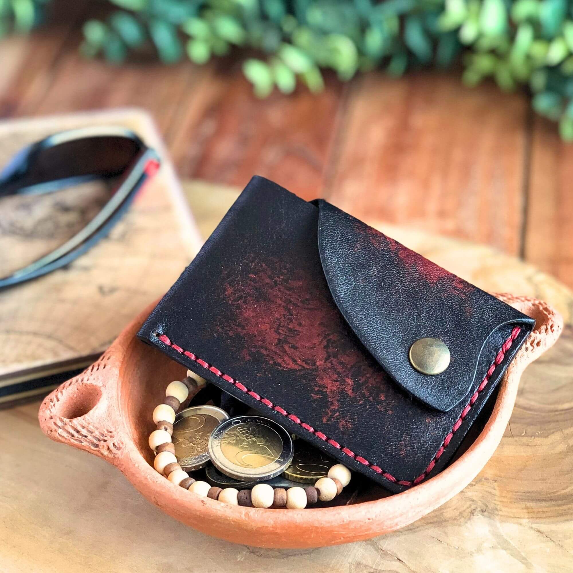 black leather minimalist card wallet in a tray with personal belongings