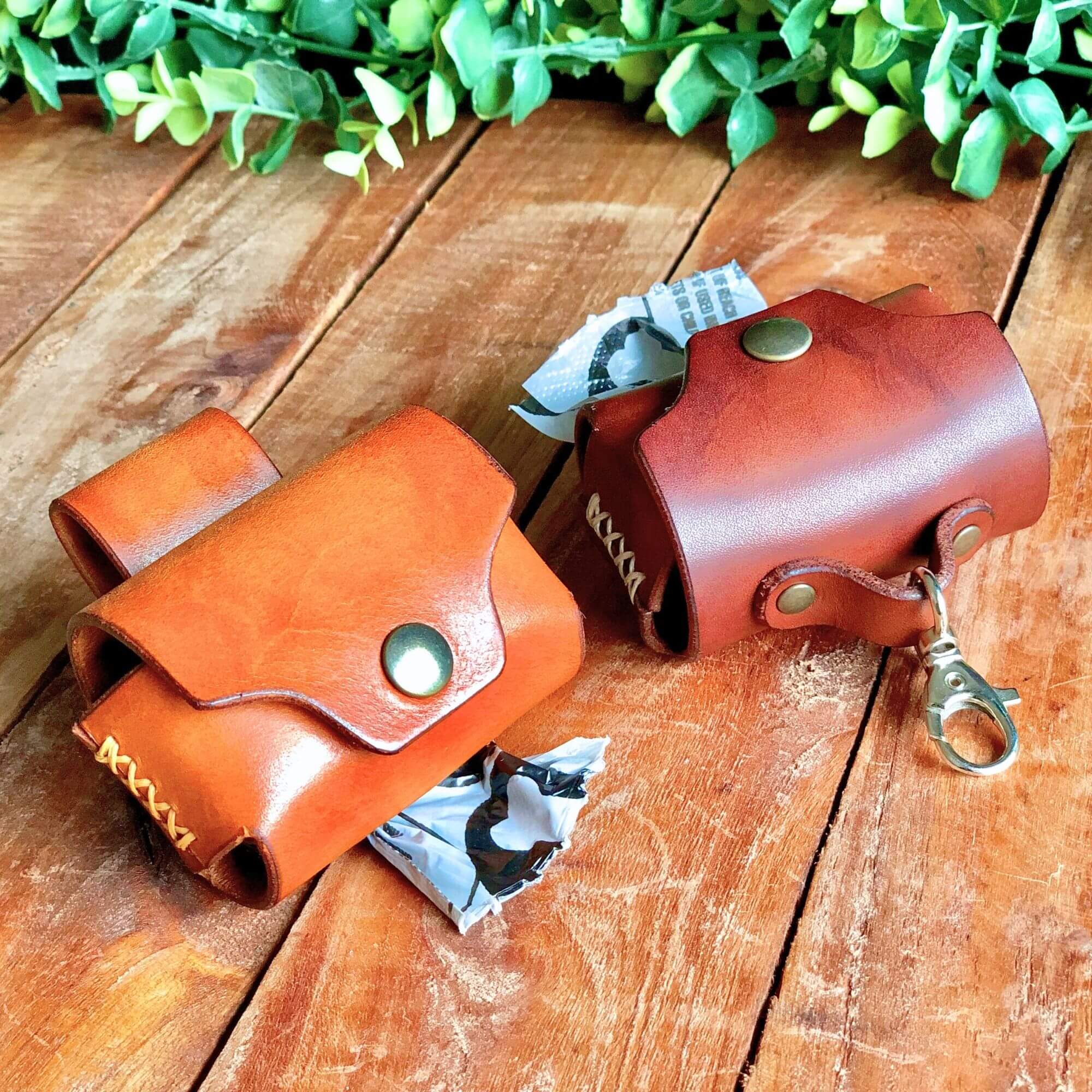 2 leather dog poop bag holders on a rustic wooden background