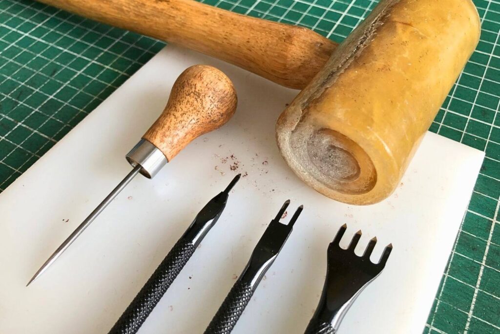 The Beginner's Leathercraft Tool Guide 3 An awl,stitching chisels, a rawhide mallet on a poly board