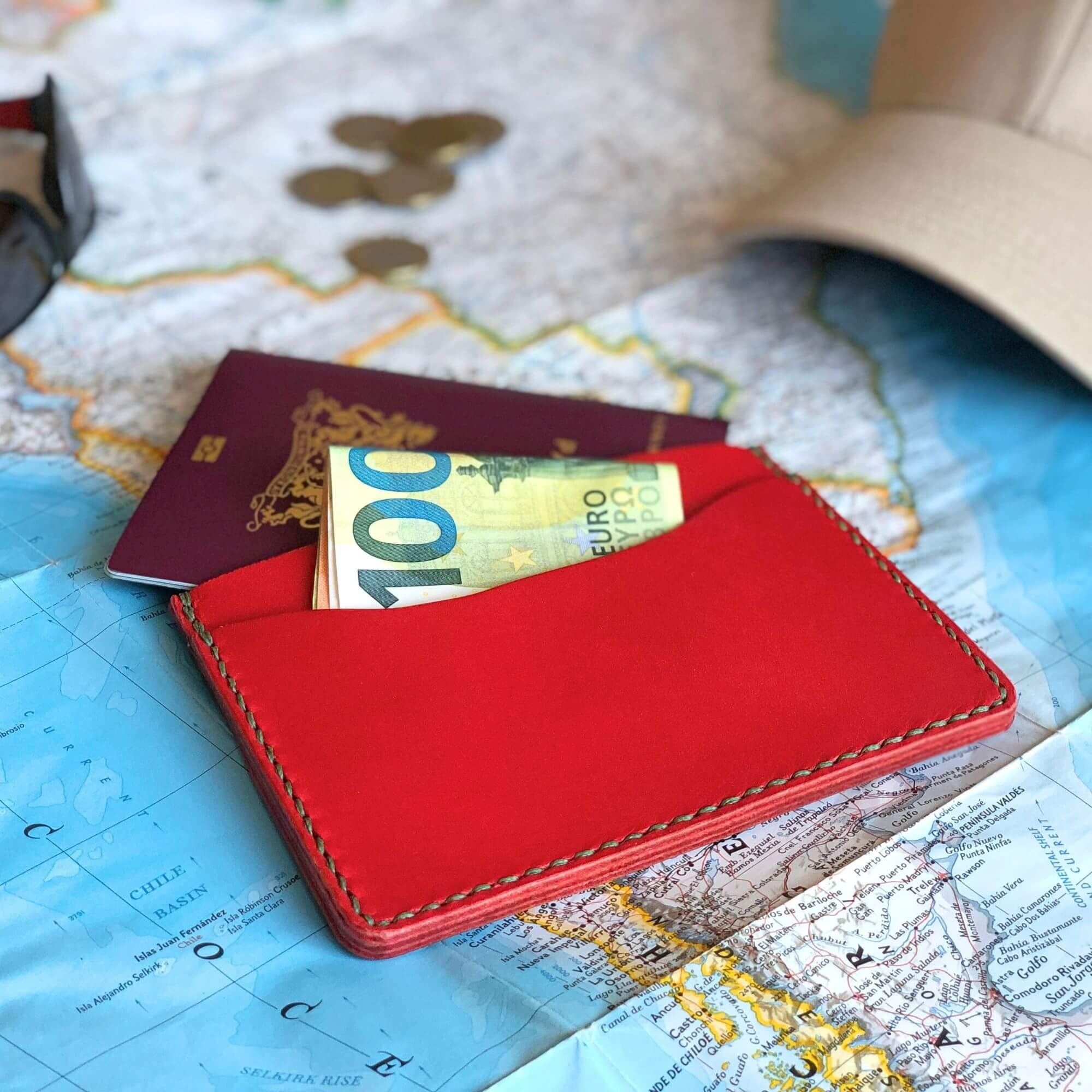Compact Passport Cover 2 red leather travel wallet filled with money and a passport on a worldmap