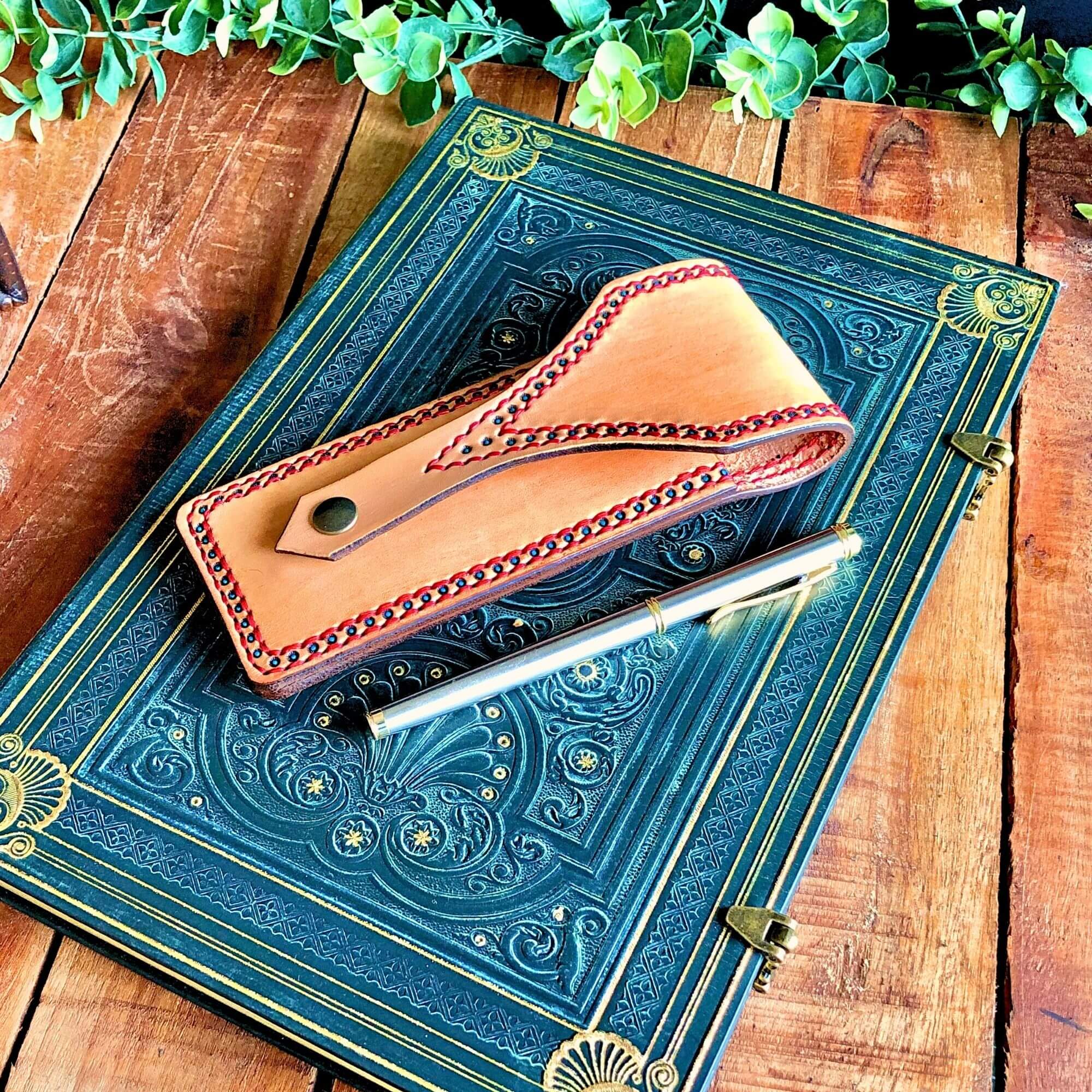 leather pen pouch with a snap closure with a pen and a notebook