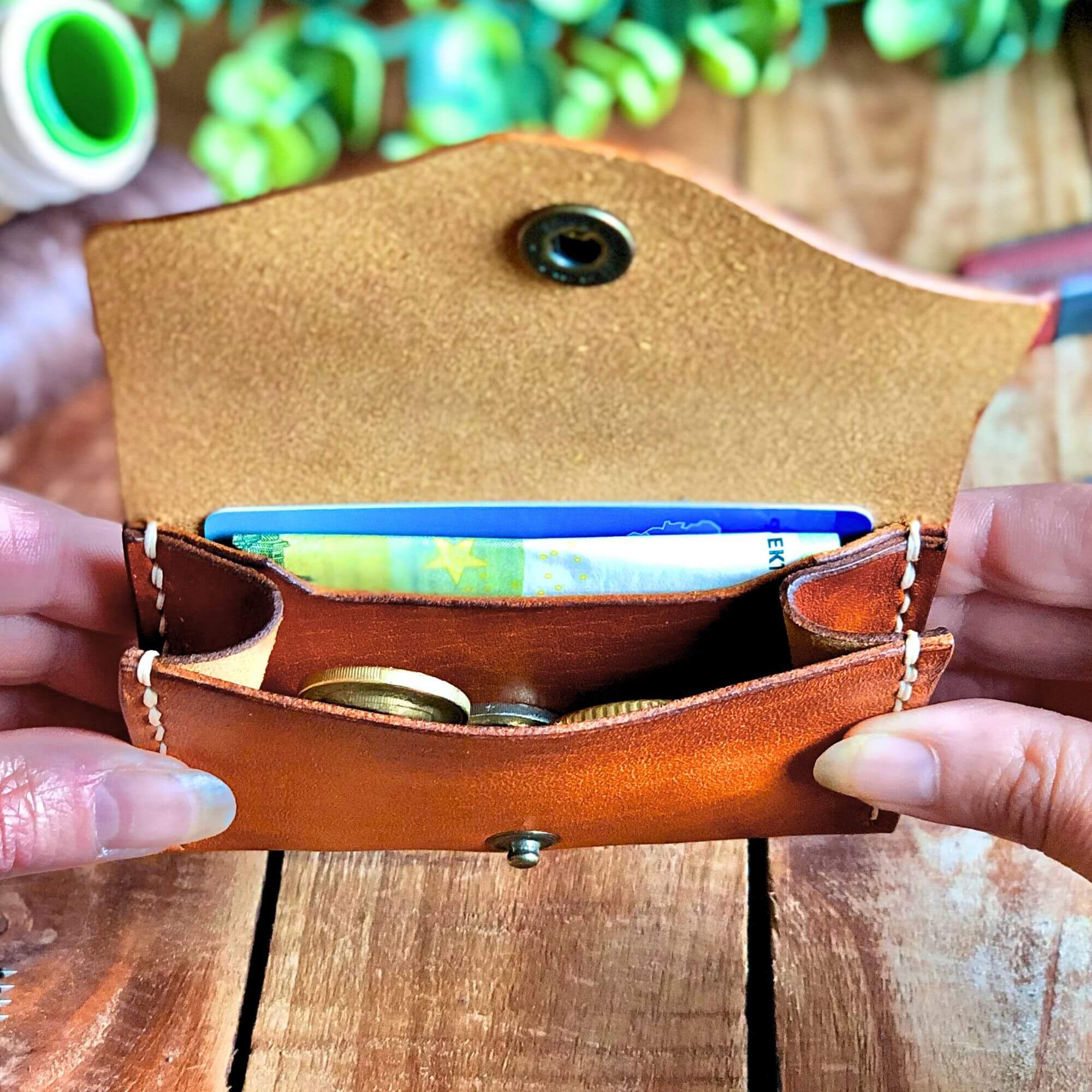 Small Wallet Bundle 12 tan leather wallet with cards and coins inside, and a snap closure held open in hands