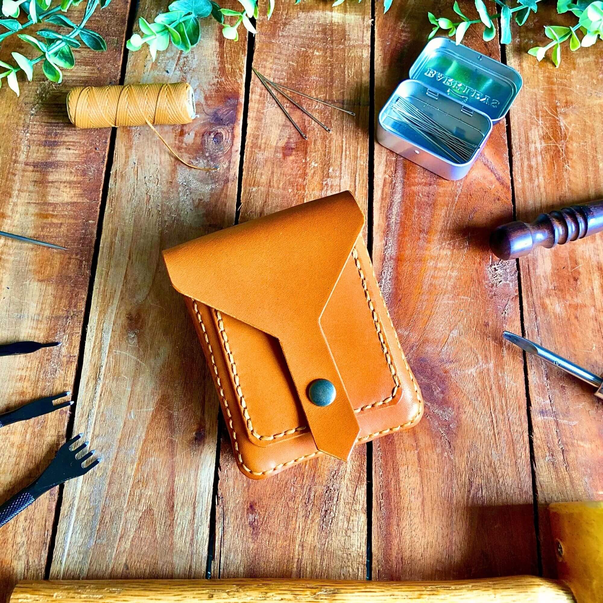 small beginner belt bag with a snap closure surrounded by leathercraft tools