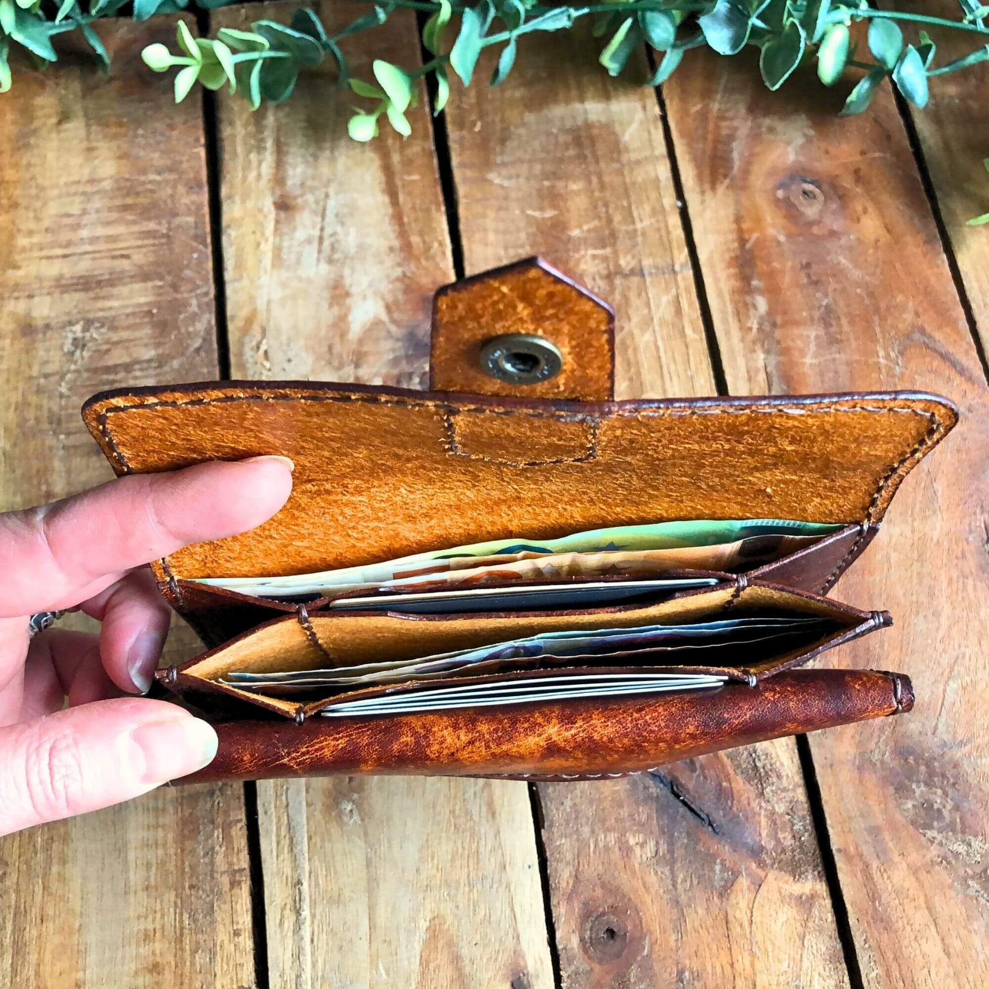 leather wallet pattern PDF by Hammer and Dye, held in hand showing bill pockets with money inside